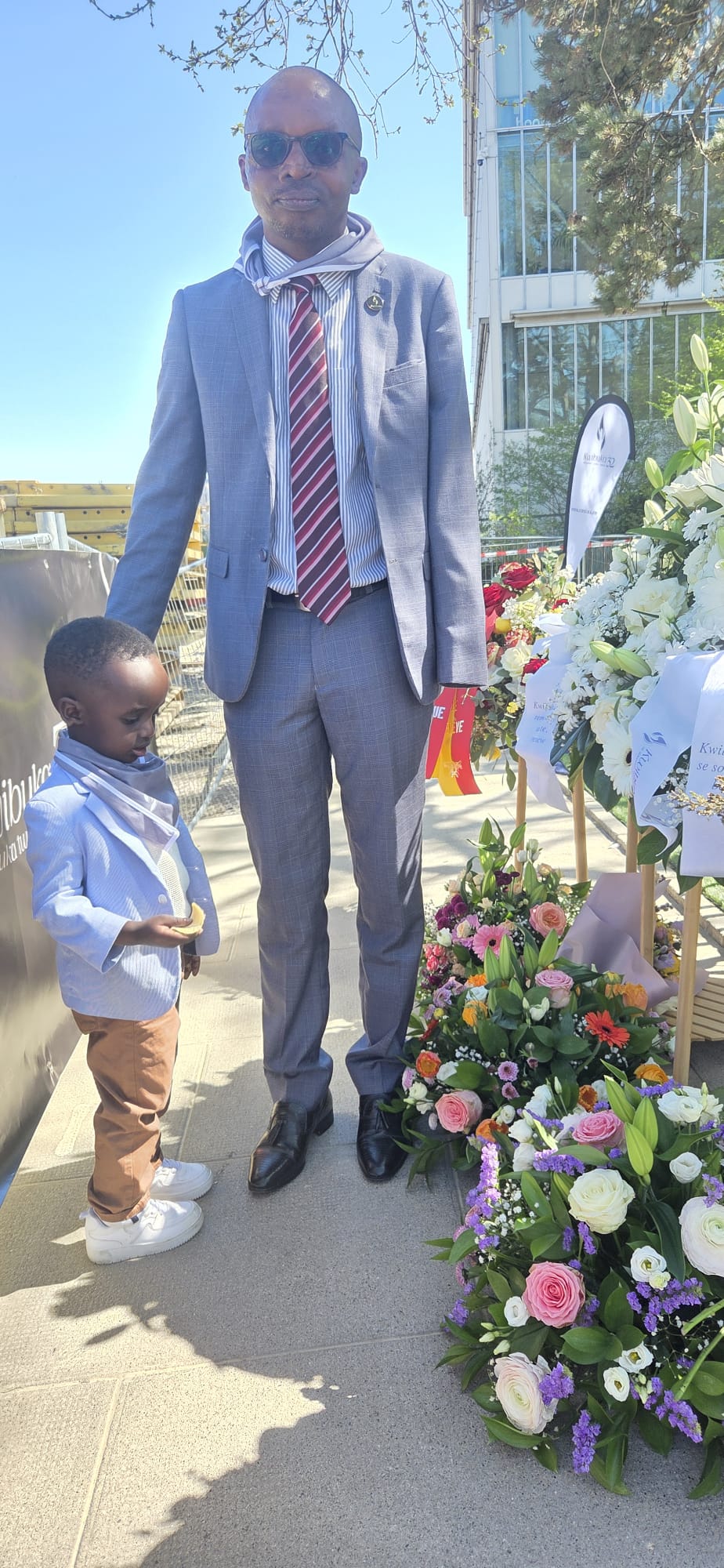 Révérien Rurangwa and his son Ethan at a Kwibuka commemoration, beside memorial flowers