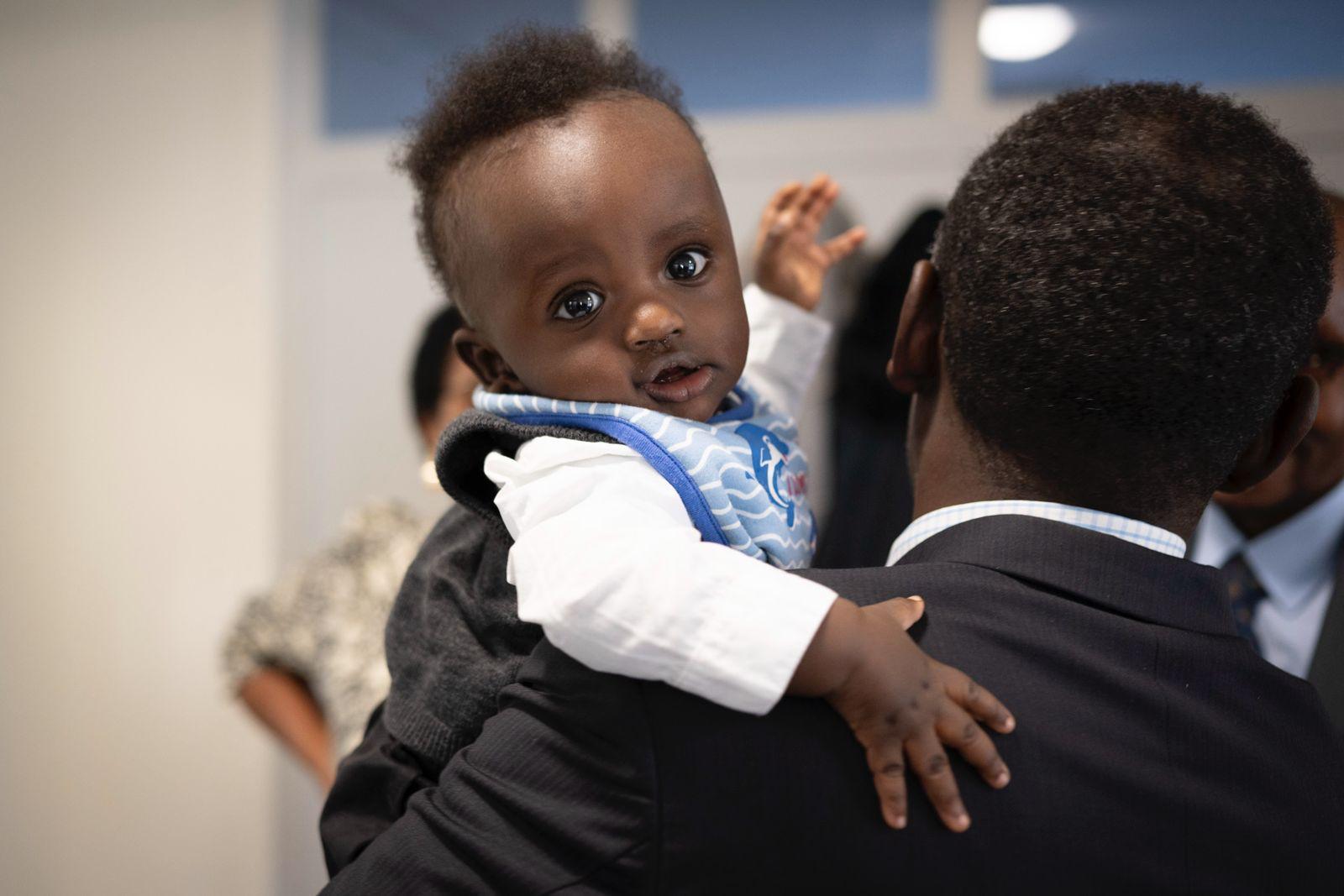 Ethan Rurangwa at his baptism, held on his father's shoulder