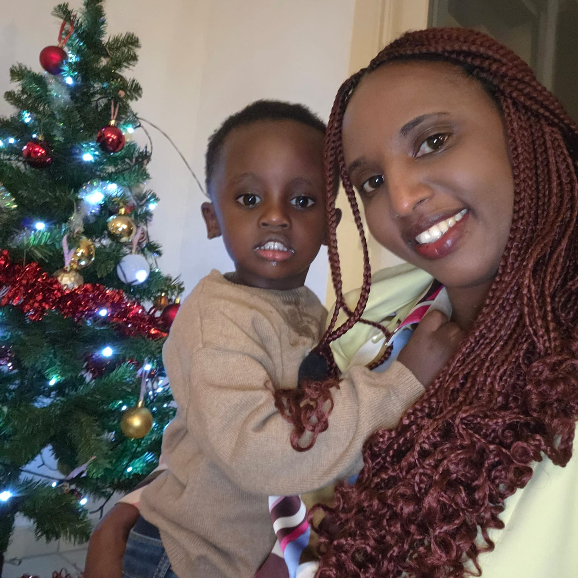 Jeanne Rurangwa holding Ethan beside a Christmas tree